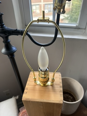Close view of the exposed bulb and brass harp on the wine-box lamp